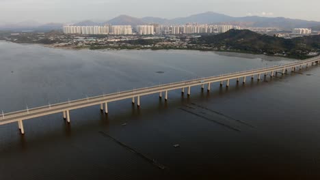 Hong-Kong-Shenzhen-Bay-Bridge-Mit-Tin-Shui-Wai-Gebäuden-Am-Horizont-Und-Fisch--Und-Austernzuchtbecken,-Luftbild