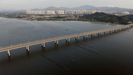 puente de la bahía de hong kong shenzhen con edificios tin shui wai en el horizonte y piscinas de cultivo de peces y ostras, vista aérea
