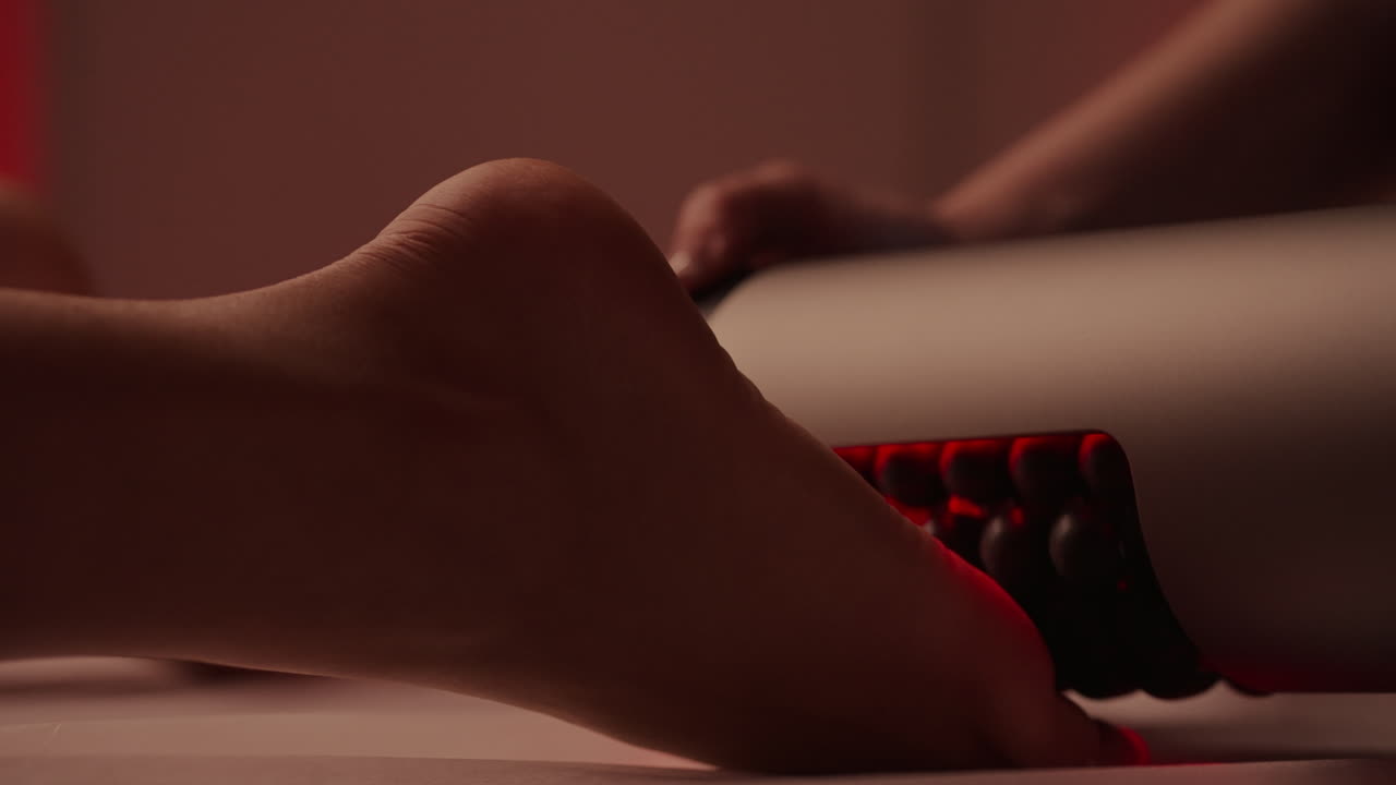 mujer recibiendo un masaje de pies con un dispositivo de terapia de luz roja