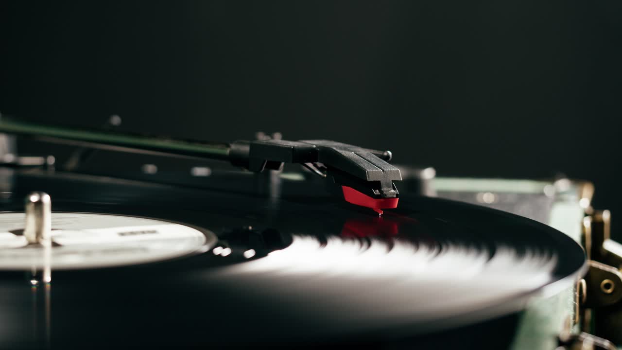 Puntina rossa che riproduce un disco in vinile nero su un giradischi