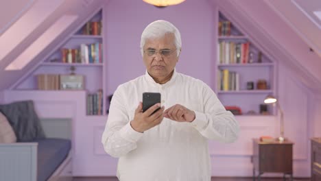 Serious-Indian-old-man-scrolling-through-phone