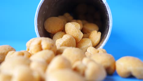 una pila de bocadillos pequeños, redondos y naranjas que se derraman de un recipiente
