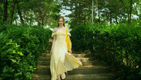 Woman-In-Yellow-Silk-Sundress-Walking-Down-The-Stairs-on-Summer-Day-in-Green-Park