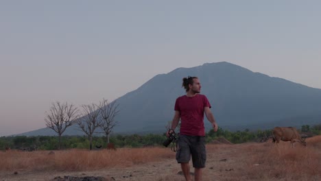 Young photographer walks towards camera in slow motion with Mount Agung in the background