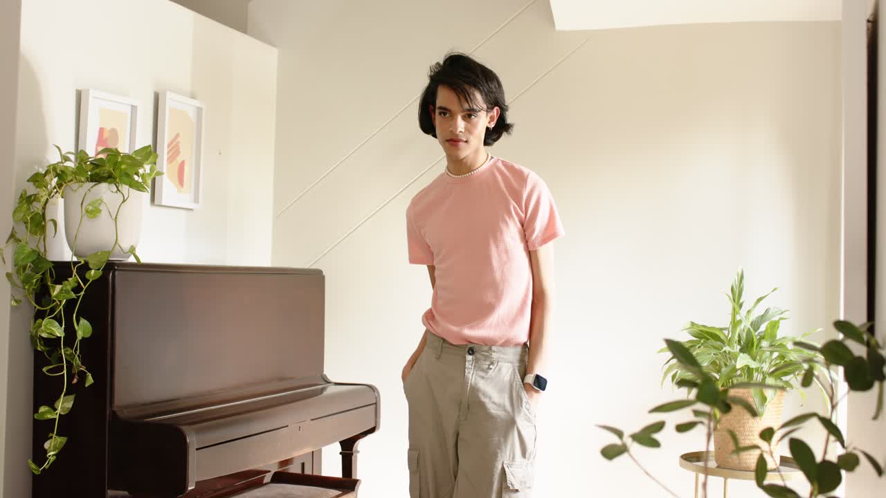 Guardando in basso, un uomo si infila le mani nelle tasche e si sistema i capelli accanto al pianoforte a casa, per sicurezza.