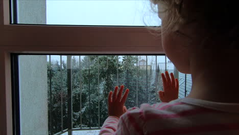 Una-Niña-Mira-Por-La-Ventana-Cómo-Cae-La-Nieve