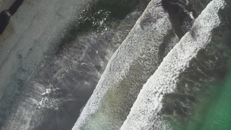 Top-down-aerial-shot-with-spinnign-motion-of-big-waves-breaking-on-Talisker-bay,-Isle-of-Skye