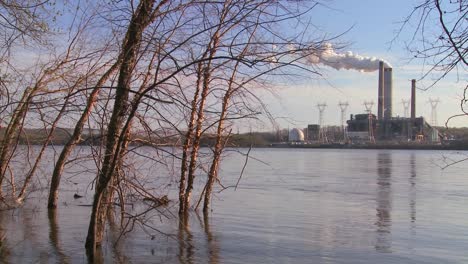 Una-Planta-De-Energía-Con-Chimeneas-Cerca-De-Un-Río.