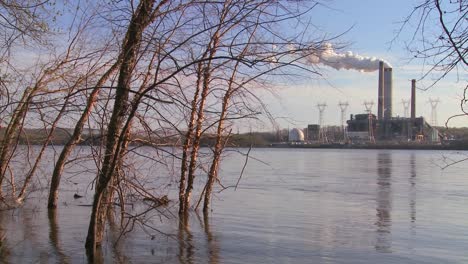 a power plant with smokestacks near a river
