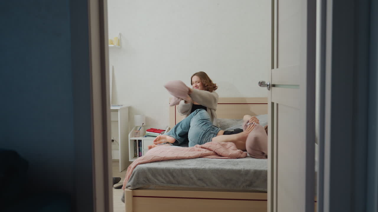 Two Young Women Enjoy Quiet Evening Together, Young Women Softly Laugh During Cozy Bedtime Gathering, Peaceful Night Scene Featuring Two Friends Smiling Near Dimly Lit Bedside Lamp