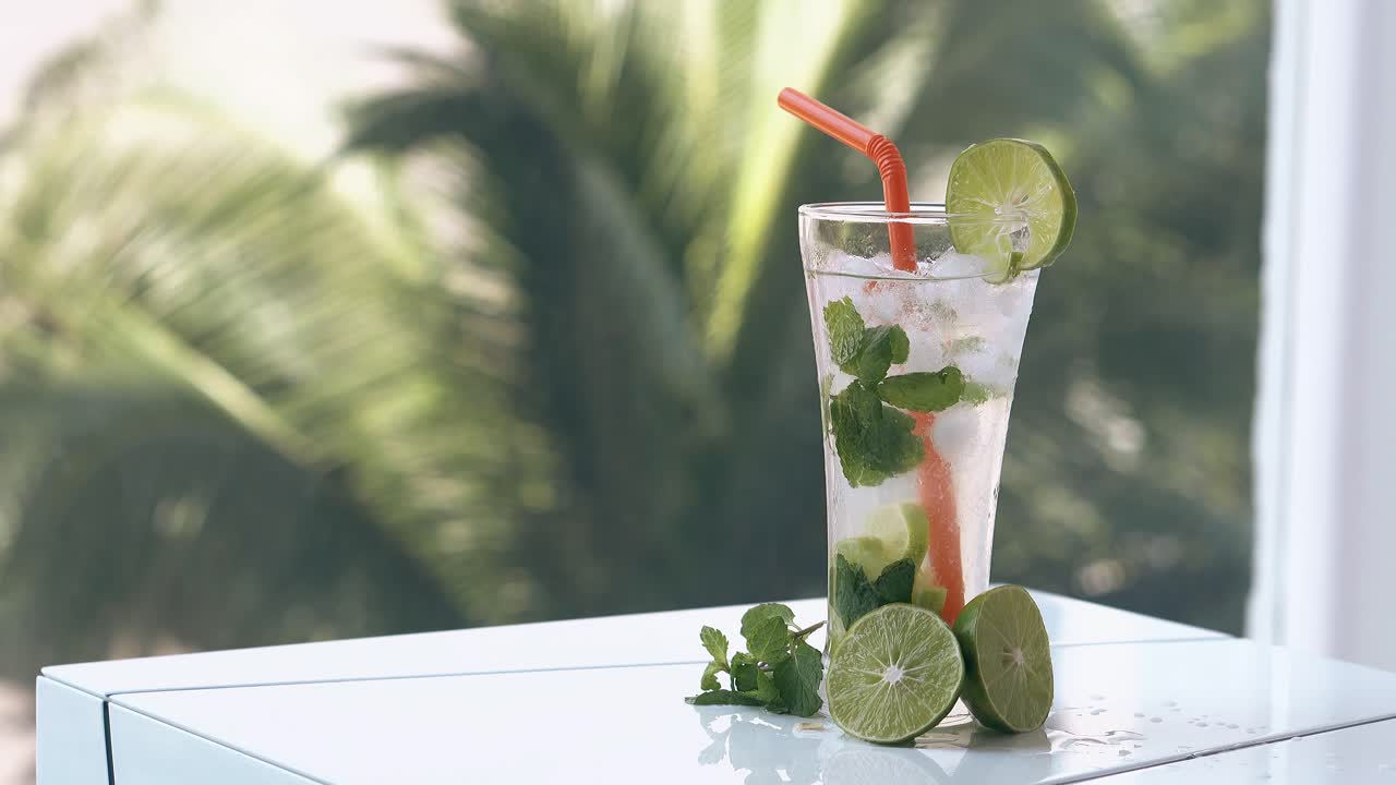 긴 초록색 종려나무 가지가 라임과 함께  ⁇ 색 테이블 뒤에 흔들린다