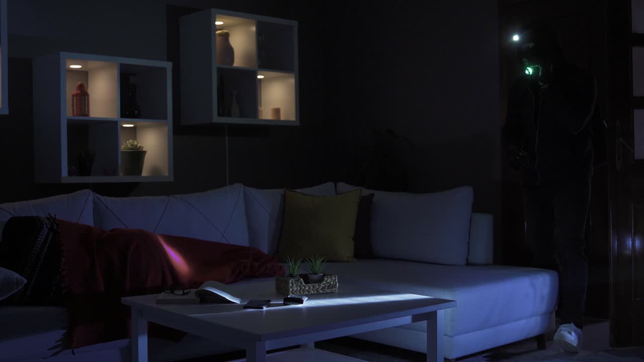 Tyv stjæler ting i hjemmet, mens en mand sover.