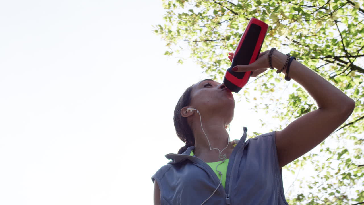 corredora mujer bebiendo botella de agua sol llamarada energía solar