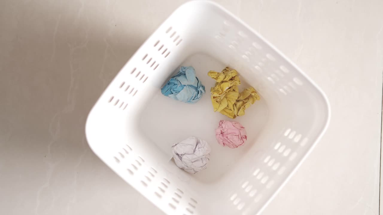 papel arrugado en un cubo de basura blanco