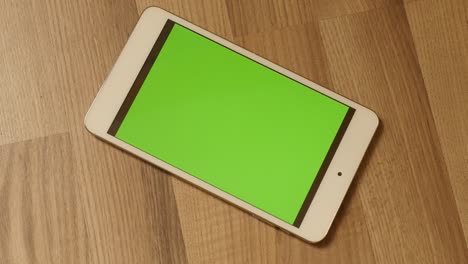 acercarse a la tableta de pantalla verde en el piso de madera