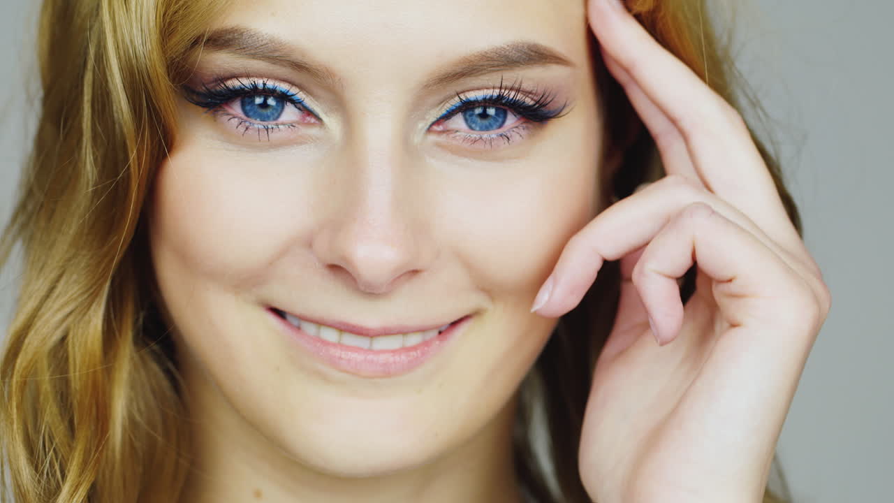 el retrato de una joven mujer de ojos azules relaciona su cara con los dedos de video hd