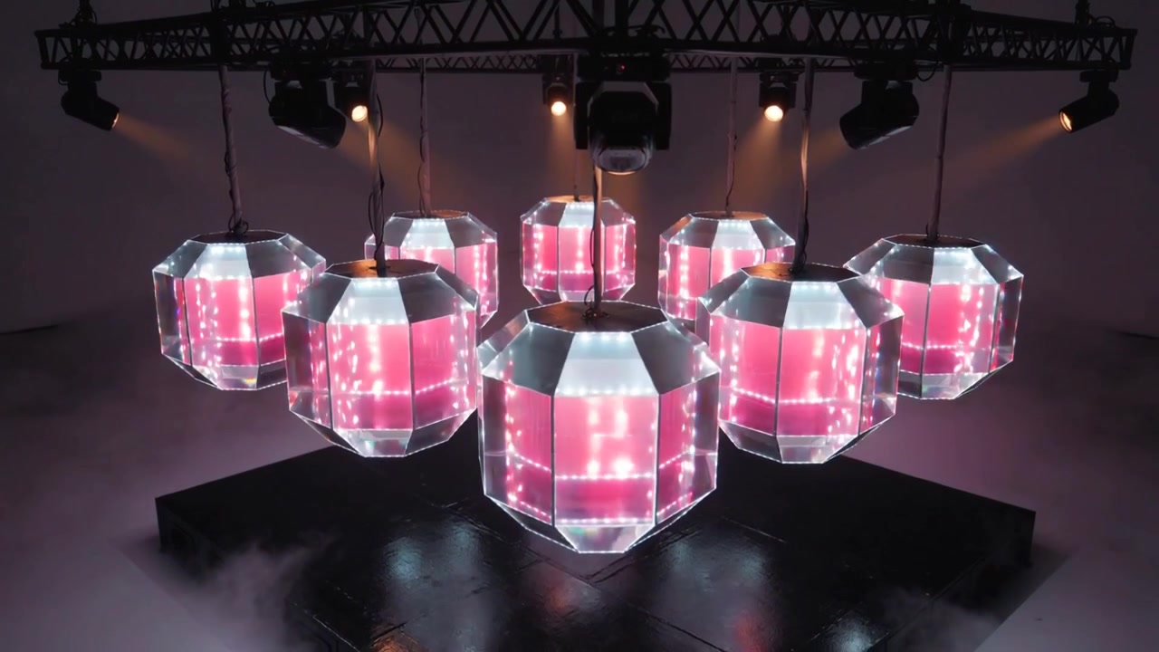 Shifting LED program cycling colors on seven faceted LEDs in studio, truss softening haze for stage