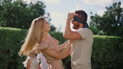 familia jugando a ciego buff en el jardín. padre feliz en ciego atrapando niño