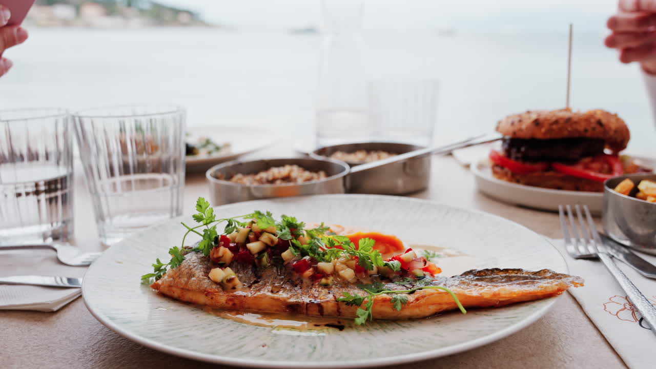 Close up of grilled fish with a sweet potato puree and a sauce on a white plate on a table at a restaurant