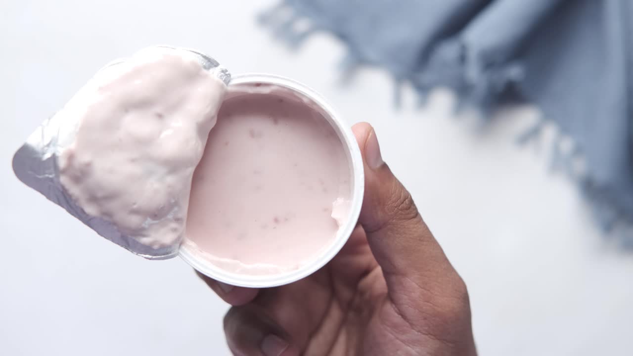 mano sosteniendo un recipiente de yogur rosado