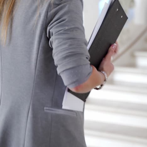 colleague with folders in her hands is running to the office on the stairs. late for work