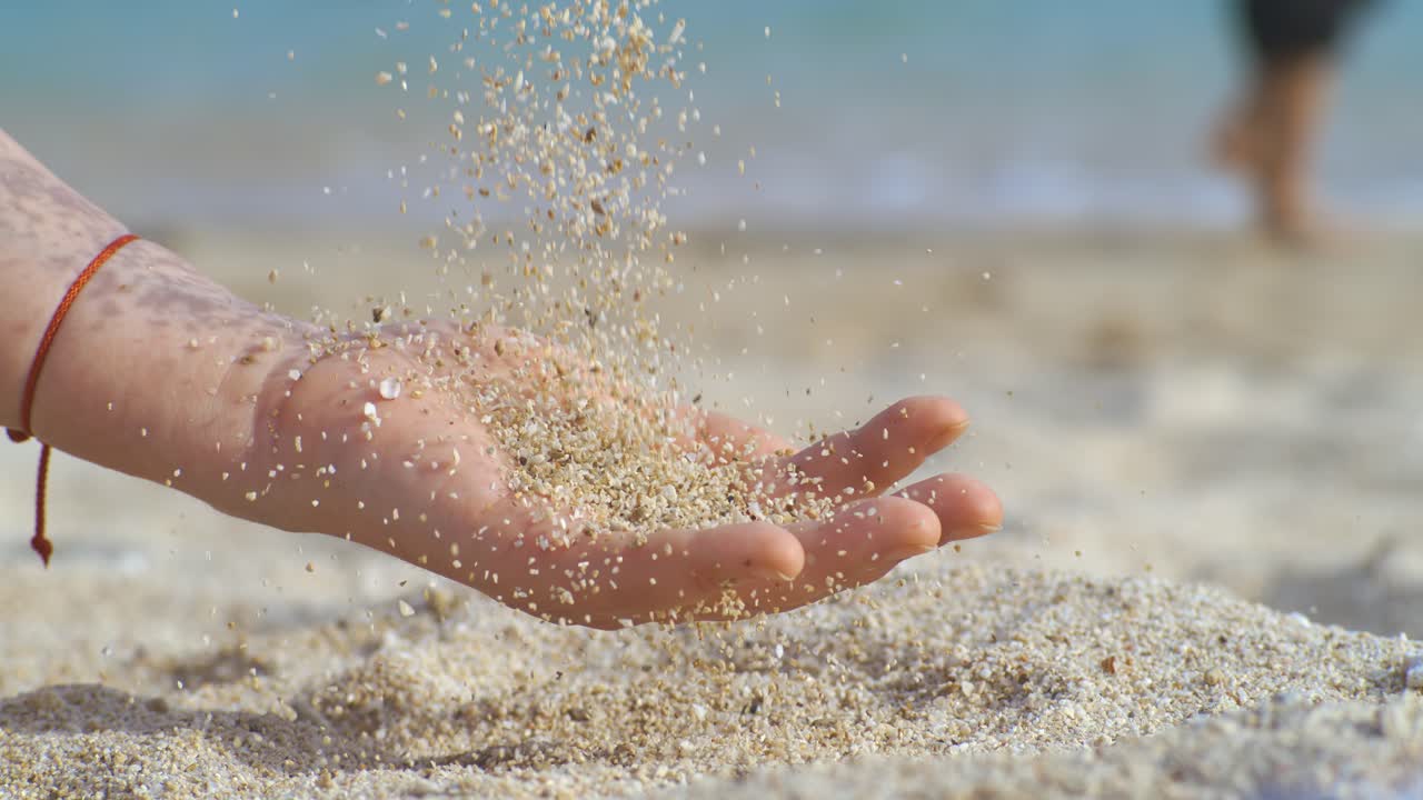 Sand falling from hand in slow motion on a beach. Vacation and travel concept. Shot on super slow motion camera 1000 fps.