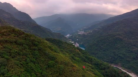 Aerial-approaching-shot-of-green-mountains-and-dam-in-Wulai-Area-during-cloudy-day,-Taipei