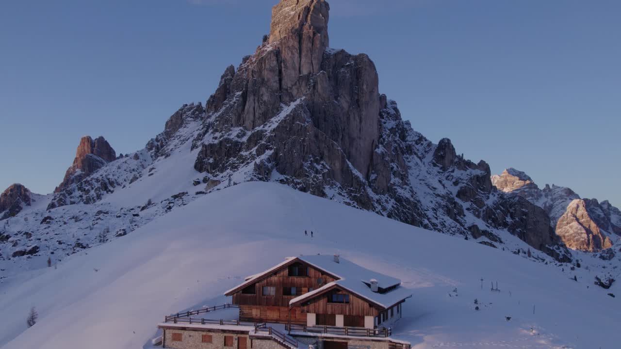 Aerial of snow-covered peaks and lodge in the Dolomites, Passo di Giau, Italy
