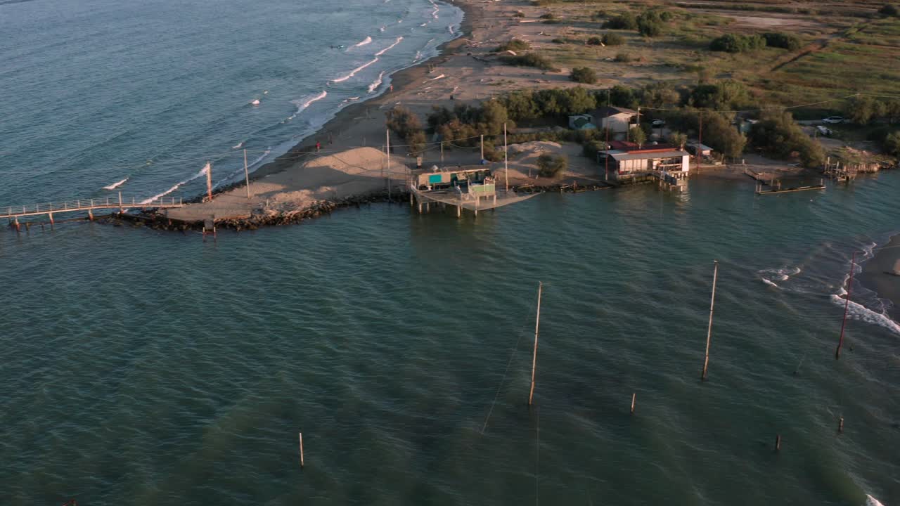 toma aérea de los valles cerca de ravenna donde el río desemboca en el mar con las típicas cabañas de pescadores al atardecer