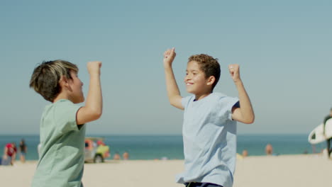 medium shot of boys rejoicing over victory in football on beach