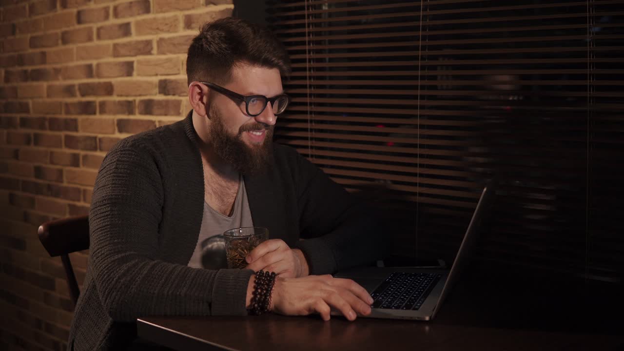 hombre trabajando en una computadora portátil en un café por la noche