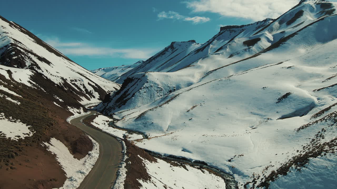 Captivating winter retreat captured by a advancing drone, showcasing snow-draped mountains and cozy glamping domes nestled amid the serene snowy landscape