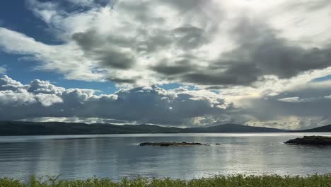 tranquil scenery of lake, mountains and clouds in rural scotland - panning shot