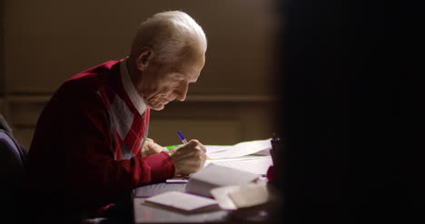 senior businessman writing on paper at table in office