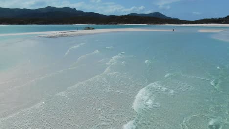 flying fast and low over small calm waves towards people on an amazing beautiful isolated island beach