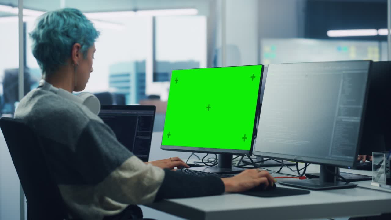 en una oficina diversa: programadora está trabajando en una computadora de pantalla verde, clave de croma y interfaz de usuario de lenguaje de codificación. empresaria digital que crea software, diseño de aplicaciones de comercio electrónico. por encima del hombro