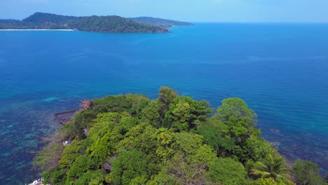 tourist boats surrounding a small tropical island in Koh Rong, Cambodia, with crystal clear water and lush vegetation. Unique aerial view flight fly reverse drone