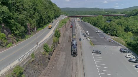 blue steam passenger train and diesel exploring the scenic railway and parking area near the mountains