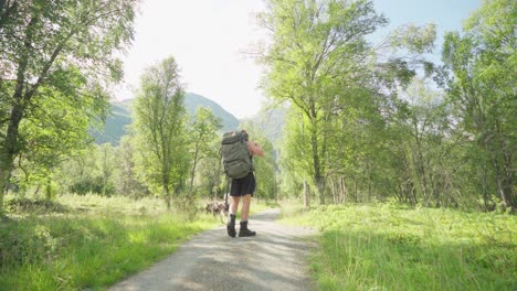 caucasian hiker drinking water in mountain path of lyngsdalen norway - wide shot