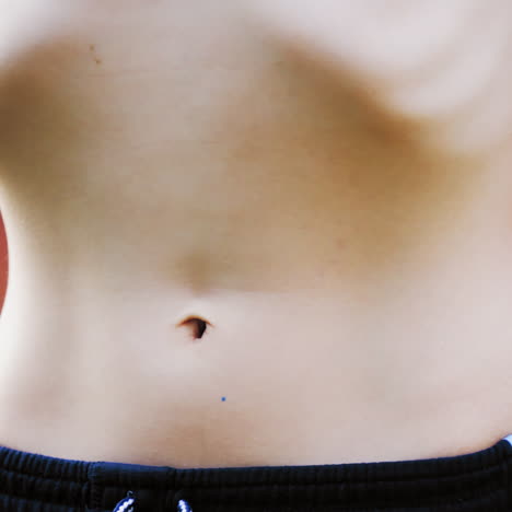 boy's stomach breathing. close-up of teenager's body in shorts isolated on green background. healthy boy shows his belly.
