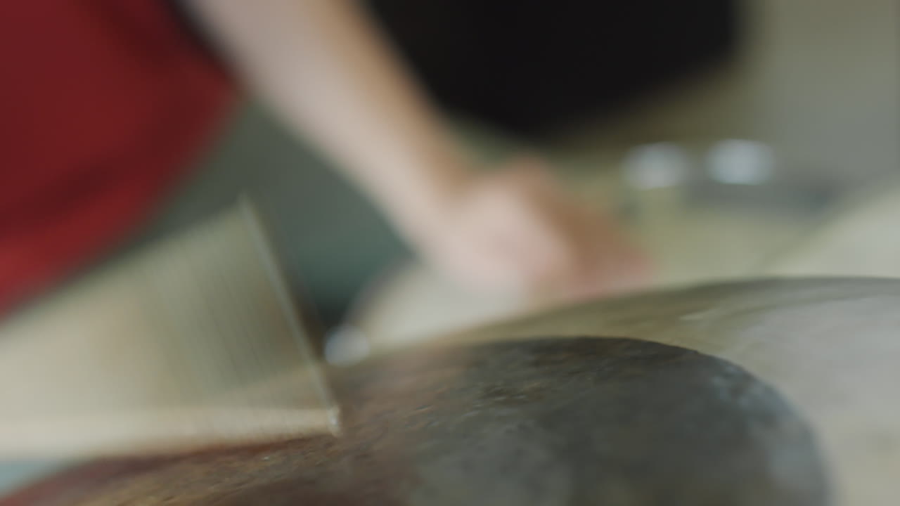 A close-up of a drumstick striking a drum, showing the action of playing