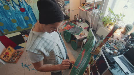 overhead view of artist painting on round canvas in creative studio