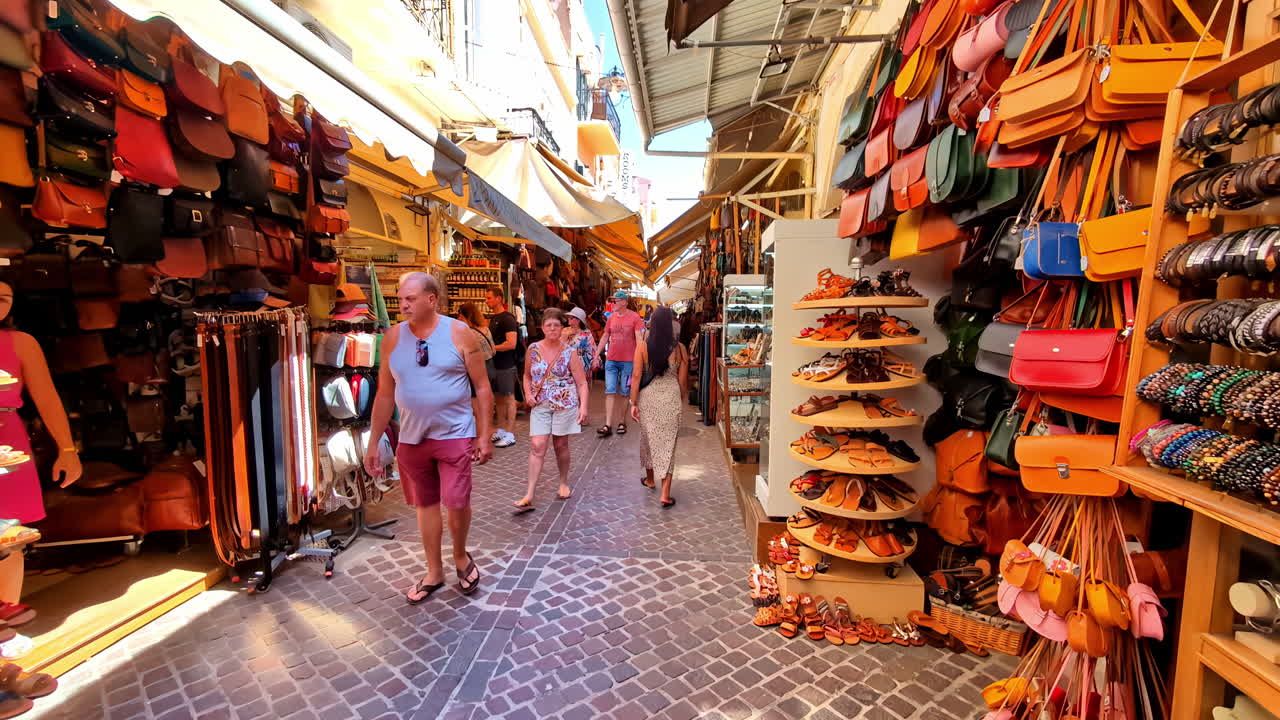 People and tourists walking and looking at products at a street market with many stalls with crafts and souvenirs from Chania in Crete Greece