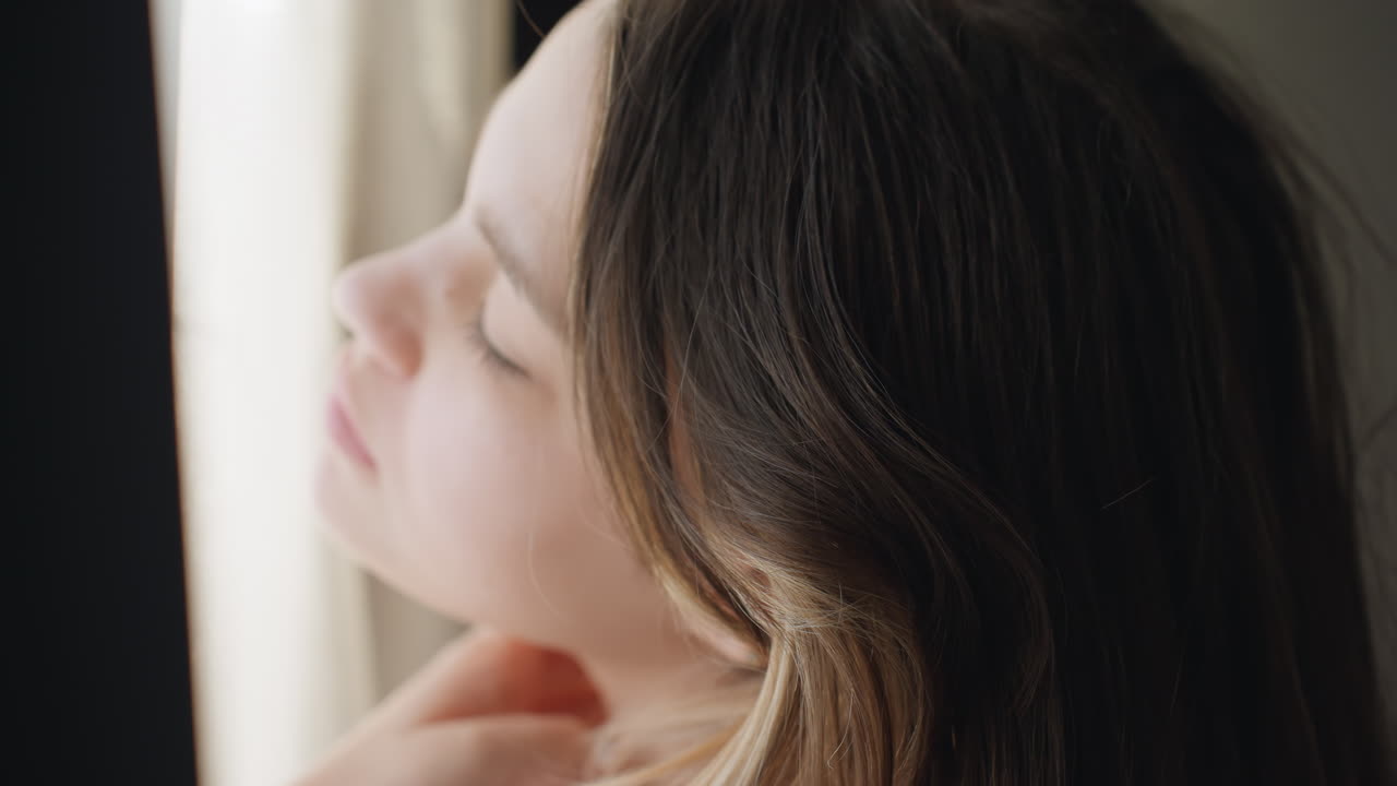 Young Woman With Closed Eyes Absorbing Soft Dawn Illumination At Window, Peaceful Girl With Delicate Facial Features Peacefully Experiencing Early Morning Light In Tranquil Bedroom Setting