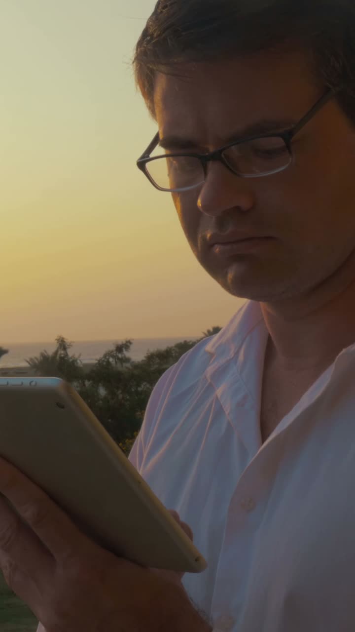 Man using a tablet at sunset