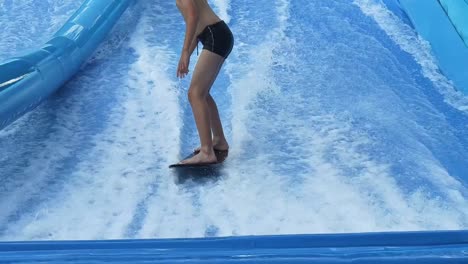 teenager surfing on an artificial wave in a water park