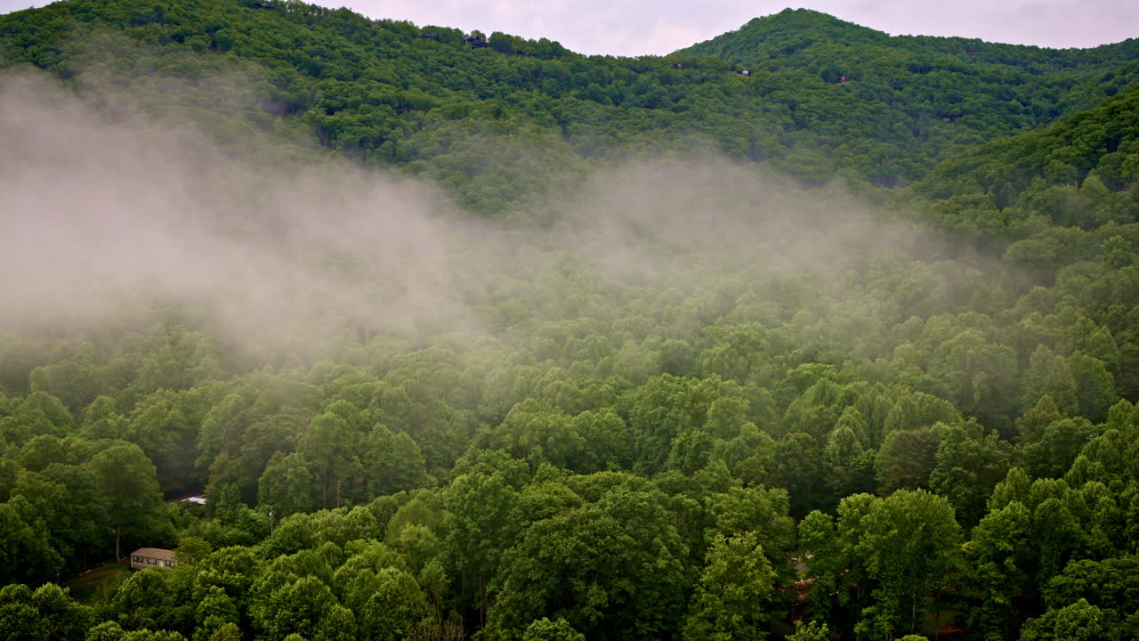 Drone flies through layers of mountain mist.