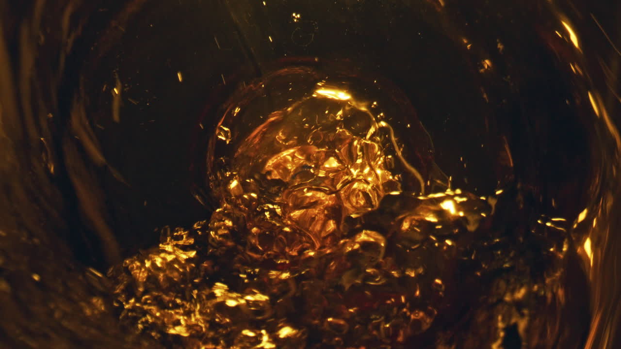 Alcohol liquid bubbling glass top view. Craft beer pouring from bottle closeup