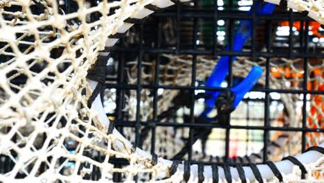 Stacked-empty-fishing-industry-lobster-net-baskets-closeup-right-dolly-looking-through-netting