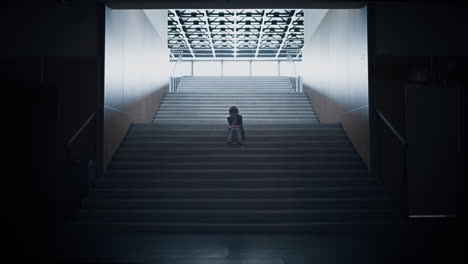 Sad teen boy silhouette sitting alone on stairway. Schoolboy feeling depressed.
